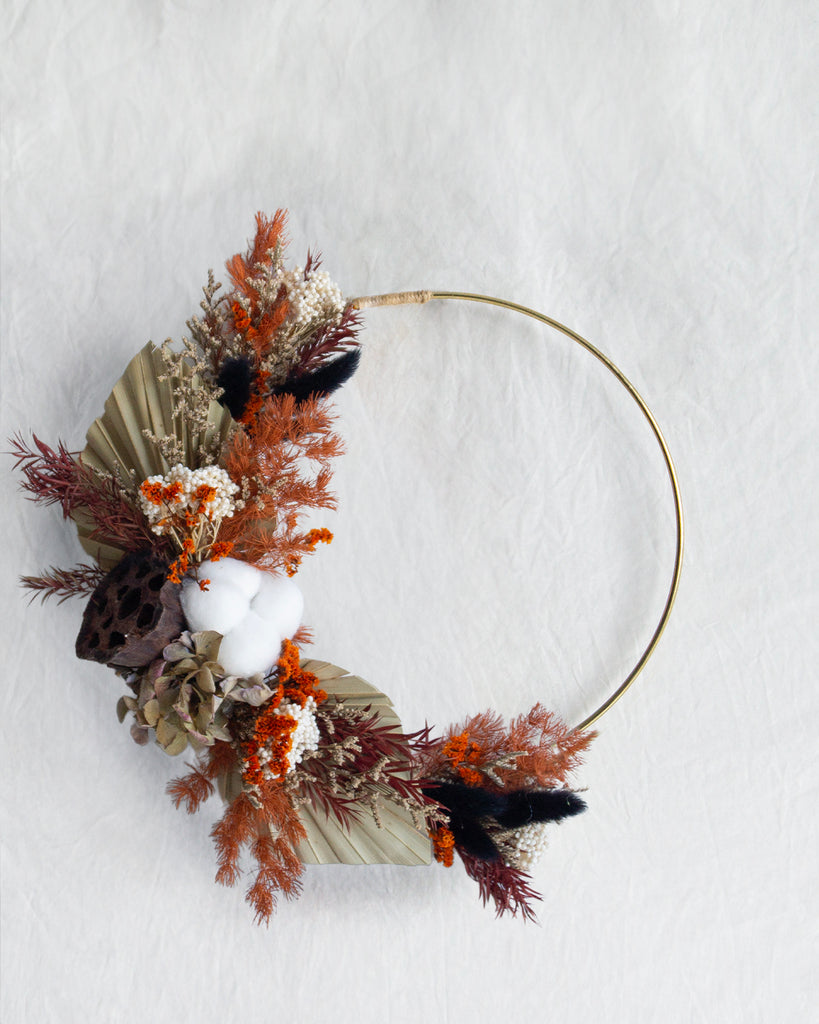 Decorative wreath with dried foliage and white flowers on a light background