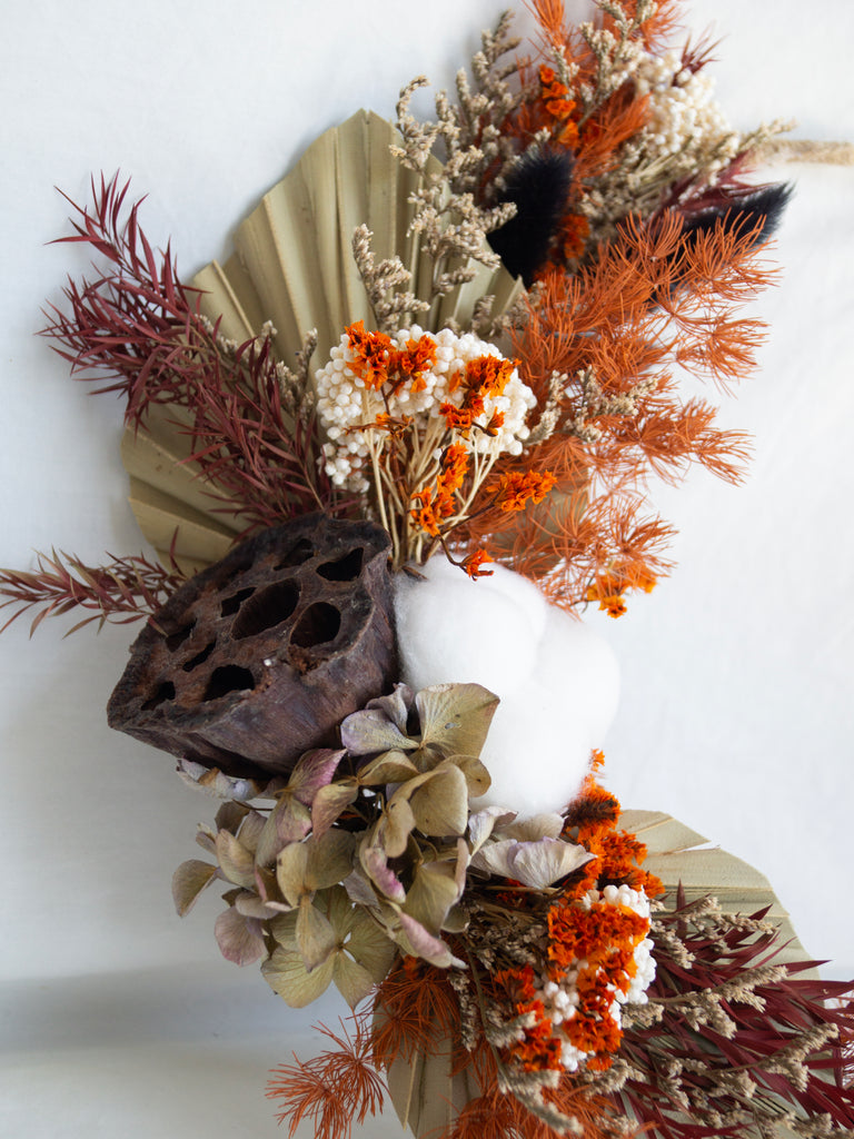 Decorative wreath with dried flowers and leaves on a white background